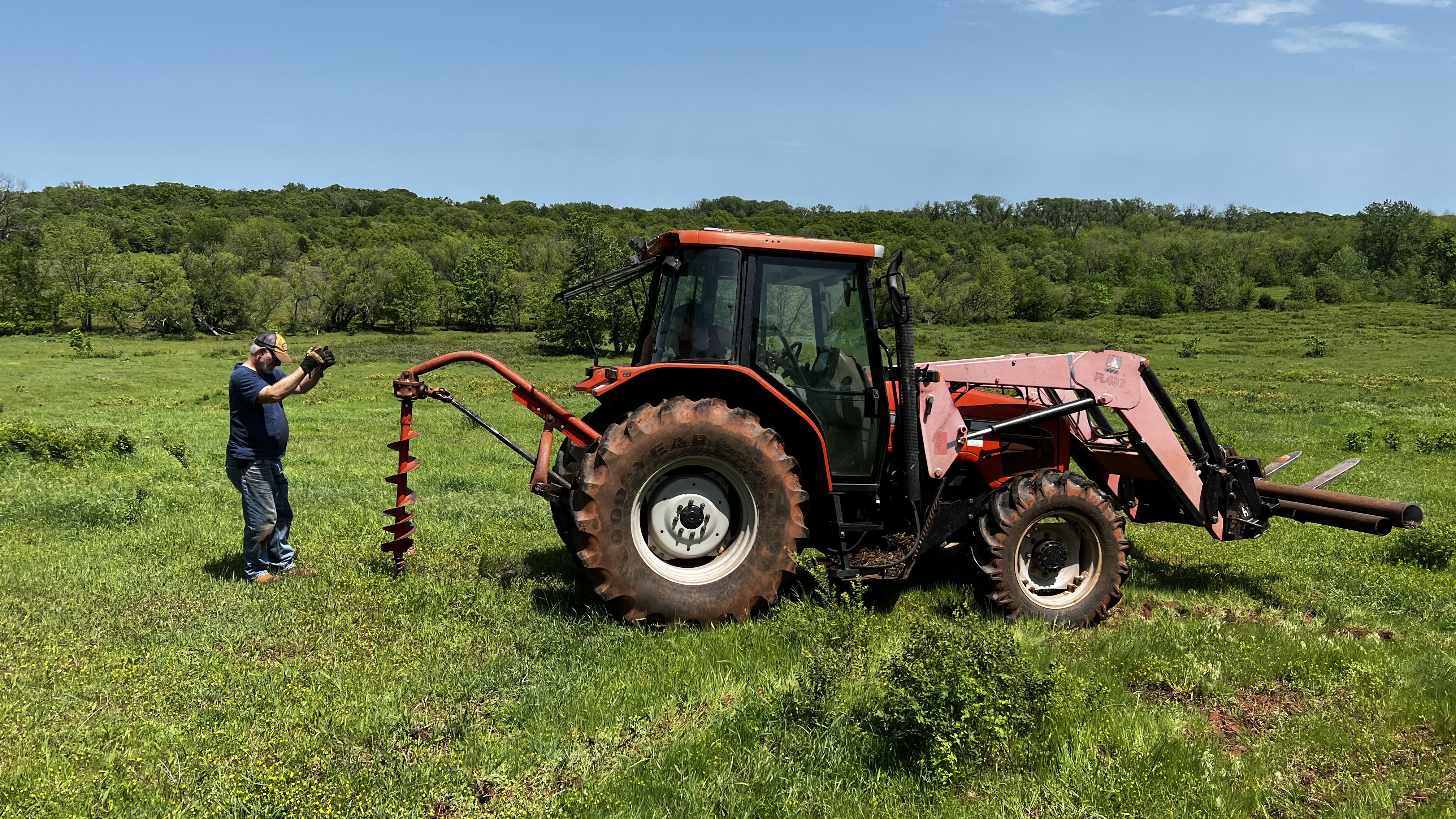 A man guiding a tractor with an auger attachment