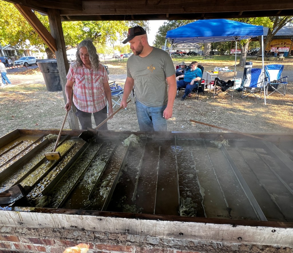 A man and woman cooking sorghum syrup.