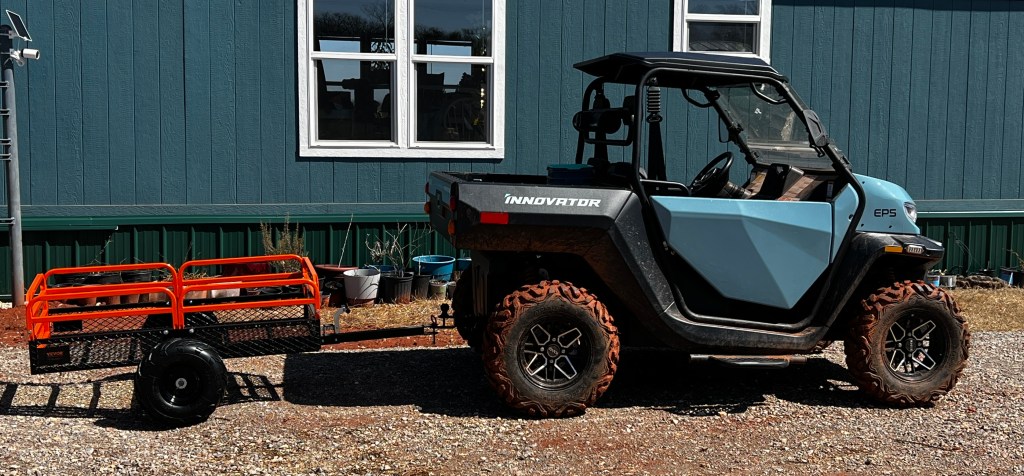 An electric UTV pulling a small garden cart.